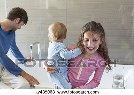 Girl smiling with her brother and her father sitting on a bathtub rim in a bathroom View Large Photo Image Stock Image - Girl smiling with her brother and her father sitting on a bathtub rim in a bathroom. Fotosearch