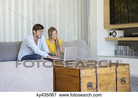 Man and his daughter sitting on a couch looking at a laptop View Large Photo Image Stock Photo - Man and his daughter sitting on a couch looking at a laptop. Fotosearch