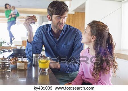 Man having breakfast with her daughter at a kitchen counter View Large Photo Image Stock Image - Man having breakfast with her daughter at a kitchen counter. Fotosearch