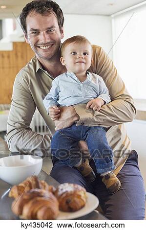 Man with his son smiling at a kitchen counter View Large Photo Image Stock Image - Man with his son smiling at a kitchen counter. Fotosearch