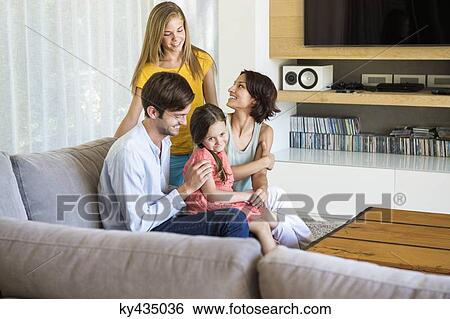 Parents with their children sitting in a living room View Large Photo Image Stock Photograph - Parents with their children sitting in a living room. Fotosearch