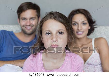 Stock Image - Portrait of a girl with her parents in the background. Fotosearch