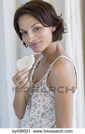 Stock Image - Portrait of a woman eating rice cake. Fotosearch