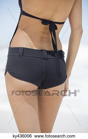 Rear view of a woman standing on the beach View Large Photo Image Stock Photograph - Rear view of a woman standing on the beach. Fotosearch