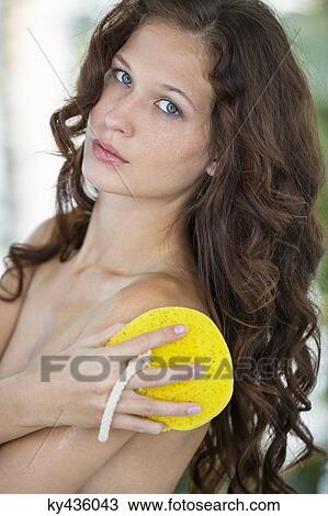 Stock Image - Woman cleaning her body with bath sponge. Fotosearch