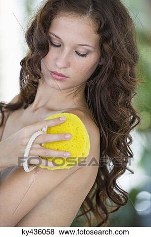 Stock Photo - Woman cleaning her body with bath sponge. Fotosearch