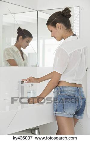 Woman filling a glass of water at bathroom sink View Large Photo Image Stock Photo - Woman filling a glass of water at bathroom sink. Fotosearch