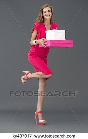 Stock Photo - Portrait of a woman carrying boxes and smiling. Fotosearch