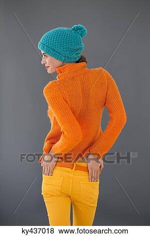 Stock Photo - Rear view of a woman standing with her hands in her pockets. Fotosearch