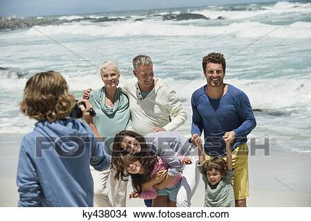 Boy filming his family with a home video camera on the beach View Large Photo Image Picture - Boy filming his family with a home video camera on the beach. Fotosearch