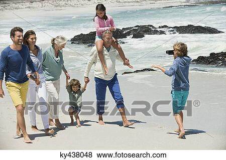 Boy filming his family with a home video camera on the beach View Large Photo Image Stock Photo - Boy filming his family with a home video camera on the beach. Fotosearch