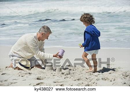 Stock Photo - Boy playing with his grandfather on the beach. Fotosearch