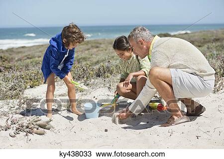 Children playing in sand with their grandfather on the beach View Large Photo Image Stock Image - Children playing in sand with their grandfather on the beach. Fotosearch