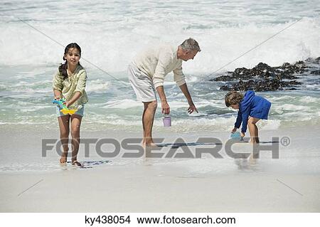 Children playing with their grandfather on the beach View Large Photo Image Picture - Children playing with their grandfather on the beach. Fotosearch