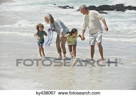 Stock Photo - Children walking with their grandparents on the beach. Fotosearch