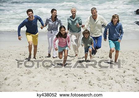 Stock Image - Family running on the beach. Fotosearch