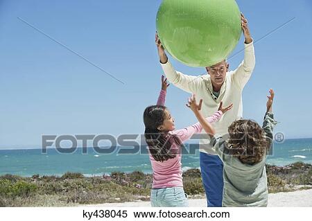 Stock Photography - Man playing with his grandchildren on the beach. Fotosearch