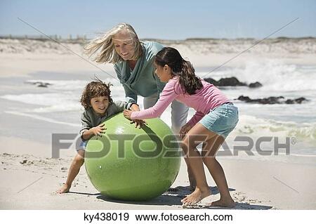 Stock Photo - Woman playing with her grandchildren on the beach. Fotosearch