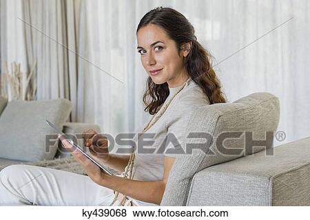 Beautiful woman using a digital tablet on a couch View Large Photo Image Stock Photo - Beautiful woman using a digital tablet on a couch. Fotosearch