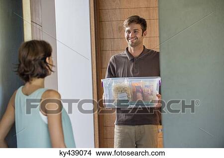 Delivery man delivering parcel to a woman View Large Photo Image Picture - Delivery man delivering parcel to a woman. Fotosearch
