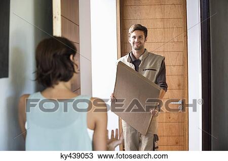 Delivery man delivering parcel to a woman View Large Photo Image Stock Image - Delivery man delivering parcel to a woman. Fotosearch