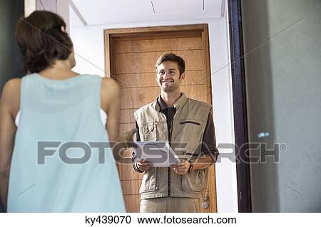 Delivery man delivering parcel to a woman View Large Photo Image Stock Image - Delivery man delivering parcel to a woman. Fotosearch