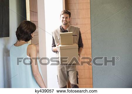 Stock Photo - Delivery man delivering parcel to a woman. Fotosearch