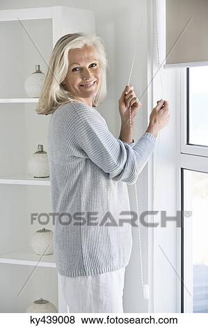 Woman adjusting window curtain View Large Photo Image Stock Photo - Woman adjusting window curtain. Fotosearch
