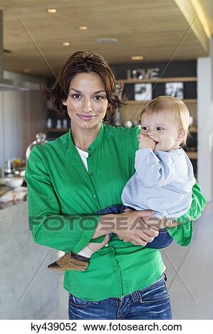 Woman carrying her son and smiling at home View Large Photo Image Stock Image - Woman carrying her son and smiling at home. Fotosearch