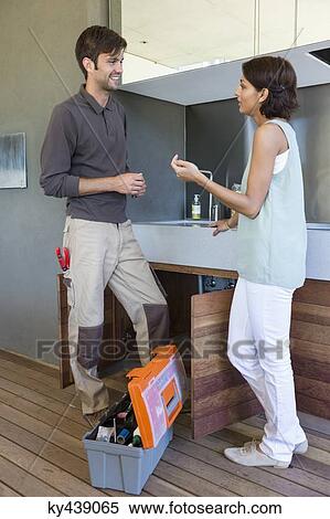 Woman discussing with a repairman in kitchen View Large Photo Image Stock Photography - Woman discussing with a repairman in kitchen. Fotosearch