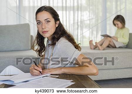 Woman doing paperwork with her daughter using a digital tablet in the background View Large Photo Image Stock Image - Woman doing paperwork with her daughter using a digital tablet in the background. Fotosearch