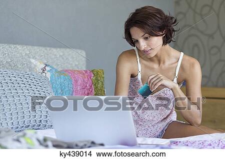 Woman holding credit card and working on a laptop View Large Photo Image Picture - Woman holding credit card and working on a laptop. Fotosearch