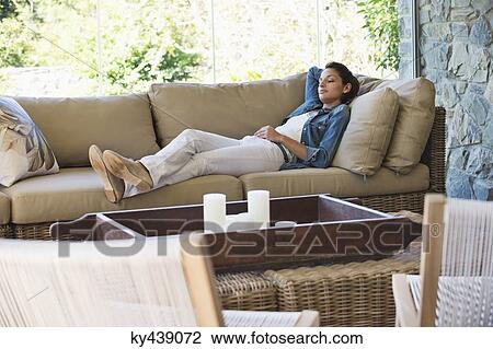 Woman lying on a couch in a living room View Large Photo Image Stock Image - Woman lying on a couch in a living room. Fotosearch