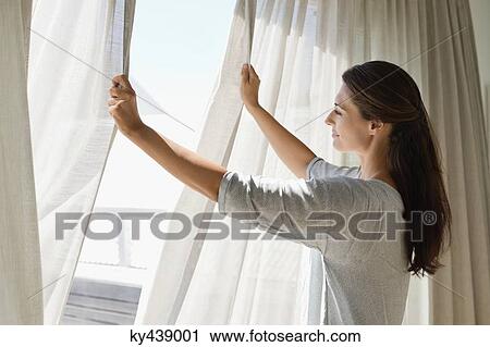 Woman opening the curtain of a window View Large Photo Image Stock Image - Woman opening the curtain of a window. Fotosearch