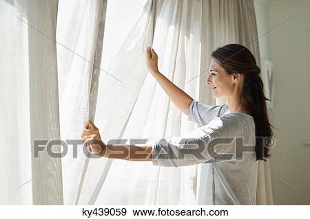 Woman opening the curtain of a window View Large Photo Image Stock Photo - Woman opening the curtain of a window. Fotosearch