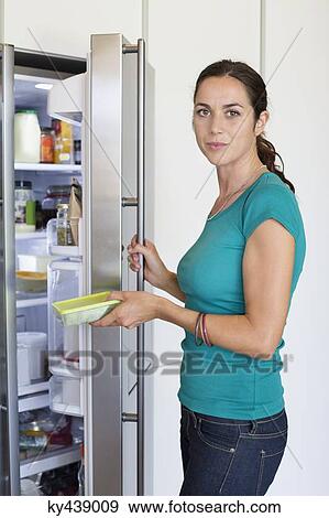 Stock Photo - Woman putting food in a refrigerator. Fotosearch