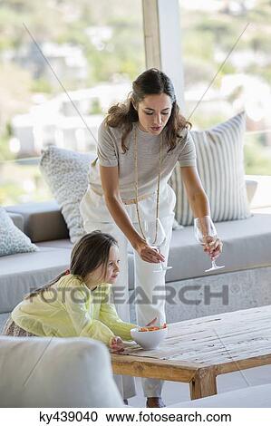Woman putting stem glasses on a table beside her daughter at home View Large Photo Image Stock Image - Woman putting stem glasses on a table beside her daughter at home. Fotosearch
