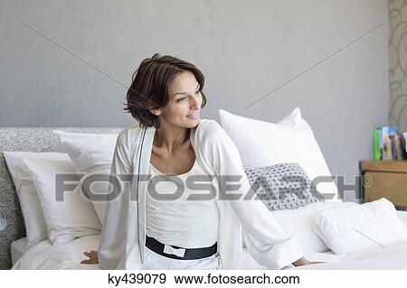 Stock Photo - Woman sitting on the bed and smiling. Fotosearch