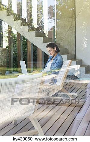 Woman using a laptop viewed through from a glass wall View Large Photo Image Stock Image - Woman using a laptop viewed through from a glass wall. Fotosearch