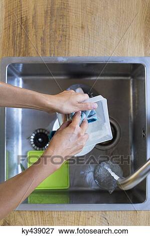 Woman washing dishes in a domestic kitchen View Large Photo Image Stock Photo - Woman washing dishes in a domestic kitchen. Fotosearch