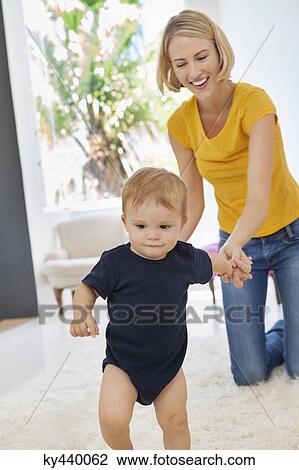 Smiling mother helping her baby to walk View Large Photo Image Stock Image - Smiling mother helping her baby to walk. Fotosearch