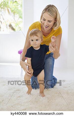 Stock Photo - Smiling mother helping her baby to walk. Fotosearch