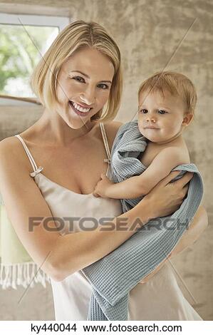 Smiling woman holding her baby in towel View Large Photo Image Picture - Smiling woman holding her baby in towel. Fotosearch