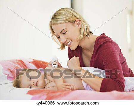 Stock Photograph - Smiling Woman looking at her sleeping baby. Fotosearch