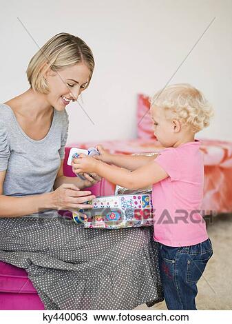 Stock Image - Smiling woman opening a box for her daughter. Fotosearch