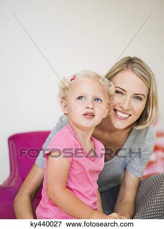 Stock Photo - Smiling woman sitting with her daughter. Fotosearch