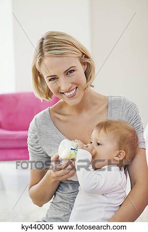Stock Photography - Woman feeding milk her baby with a bottle. Fotosearch