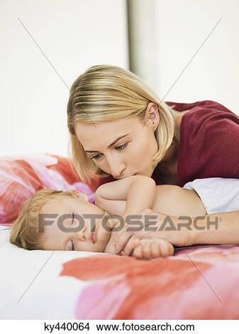 Woman kissing her baby on the bed View Large Photo Image Picture - Woman kissing her baby on the bed. Fotosearch