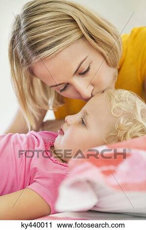 Stock Image - Woman kissing her daughter's forehead. Fotosearch