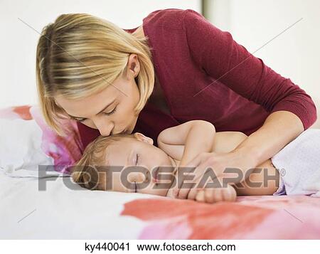 Stock Image - Woman kissing her son's forehead. Fotosearch